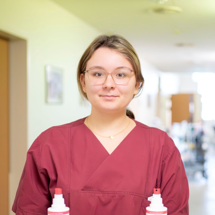 Eine Auszubildene in einem roten Kittel sieht selbstbewusst in die Kamera