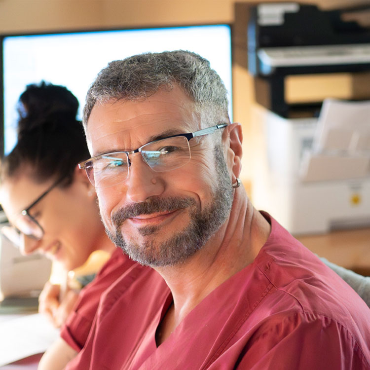 Ein freundliche Pflegerin in weißer Dienstkleidung sieht in die Kamera